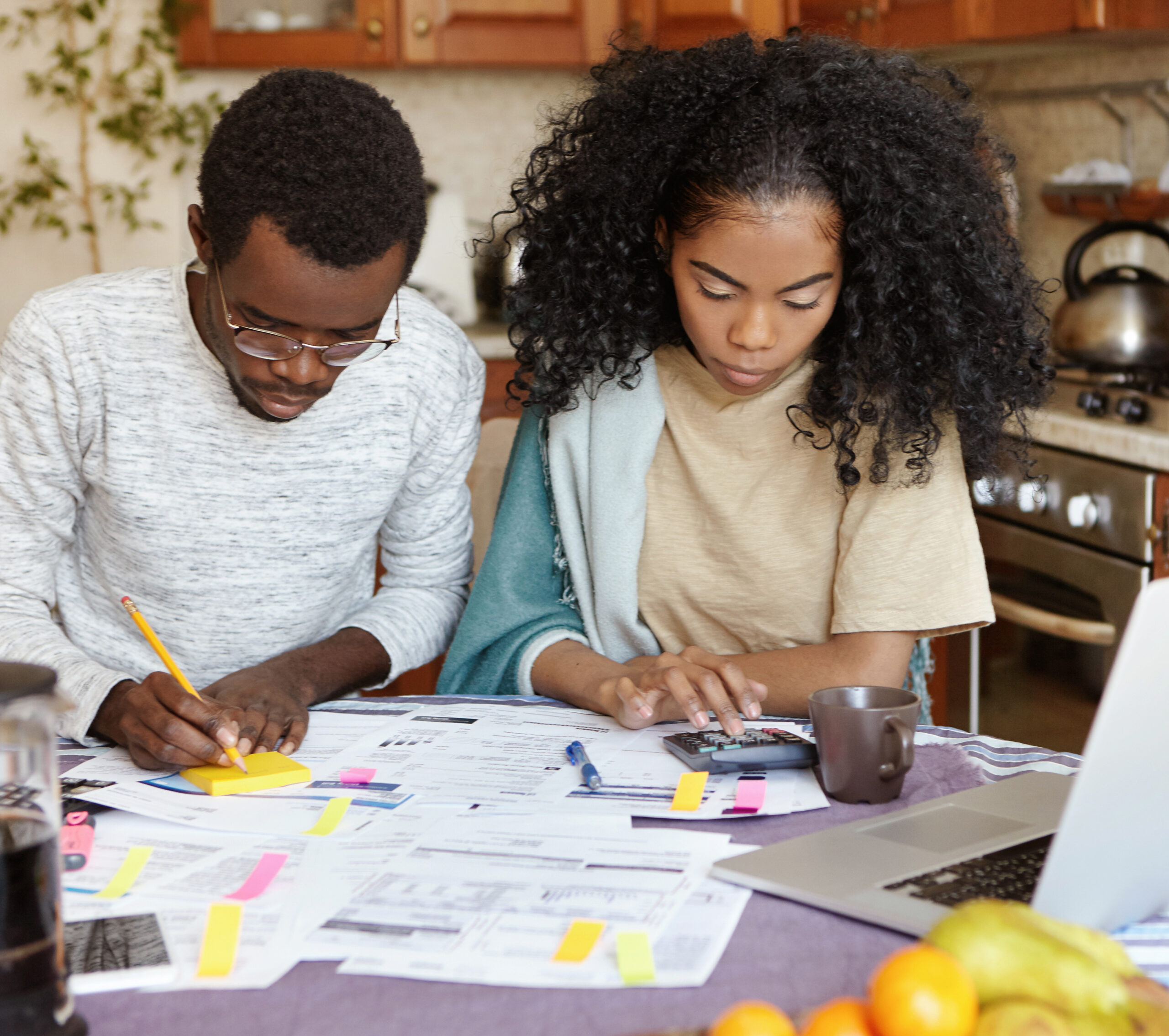 A young couple sitting at kitchen table with papers and laptop managing domestic finances together.